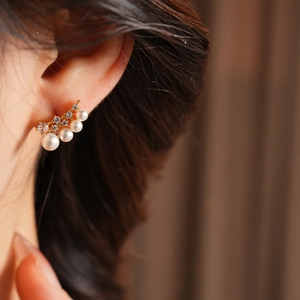 Close-up of 18k gold plated earrings with four gradient pearls and zircon stones