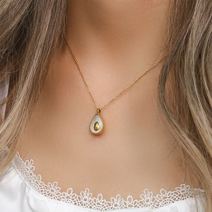 Close-up of golden avocado shell pendant necklace worn on neck by female model