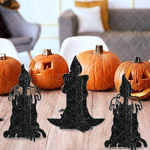Three black glitter Halloween candle silhouettes on a wooden table with pumpkins