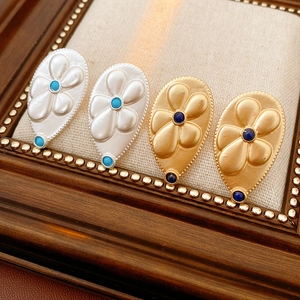 Detailed macro view of vintage water-drop earrings with flower relief and blue stones