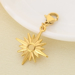 Macro shot of gold starburst charm with lobster clasp on a textured fabric background