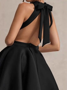 Elegant black satin backless mini dress with a large bow detail and halter neckline