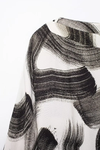 Close-up of minimalist black ink brush print on off-white chiffon dress fabric