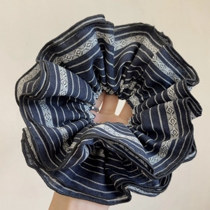 Détail d'un chouchou en tissu bleu marine avec rayures géométriques et motifs losanges