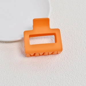 Macro view of matte orange square hair claw clip with cutout on white background