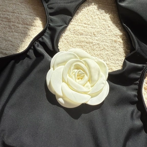 Detailed close-up of 3D white camellia flower on a black slim-fit swimsuit