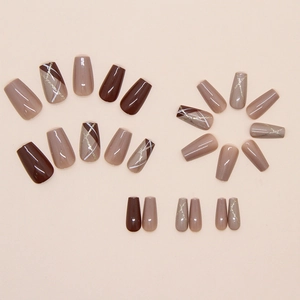 Brown coffin press-on nails with geometric white lines and gold glitter accents