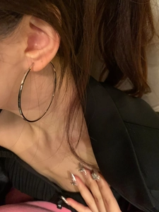 On-ear view of large silver hoop earrings showcasing the minimalist oversized round design