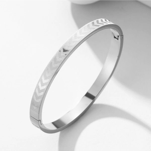 Polished silver titanium steel bangle featuring engraved arrow patterns and side clasp