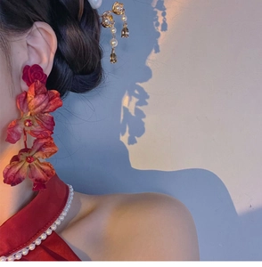 Detailed view of red rose earrings with three-layer petals worn with pearls