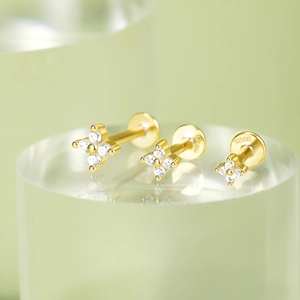 Detailed view of three gold S925 silver flower stud earrings with CZ on clear stand