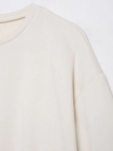 Detaillierte Nahaufnahme von Rundhalsausschnitt und Schulternaht eines beigen T-Shirts