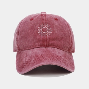 Macro detail of wine red washed cotton baseball cap with white sun embroidery texture