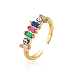 Detailed macro of 18K gold ring featuring colorful rectangle zircons and evil eye charms