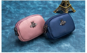 Detail view of double zipper coin purses with bee motif and pebble grain leather