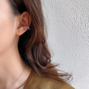 Close-up of triple-layered silver ear cuff with inlaid rhinestones on a female ear