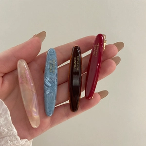 Détail de quatre barrettes ovales en acétate en rouge, bleu, écaille de tortue et irisées