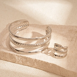 Detail of silver multi-layer open cuff bracelet and ring set with textured finish