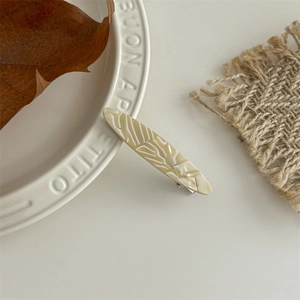 Detail of cream acetate hair clip with leaf vein pattern and handmade print on ceramic plate