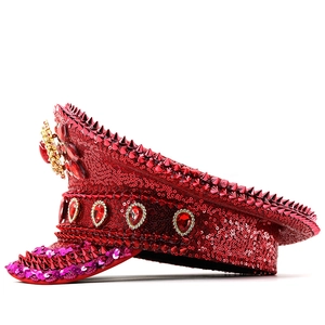 Detail of red captain hat featuring shiny sequins, cone studs, and teardrop ruby gemstones