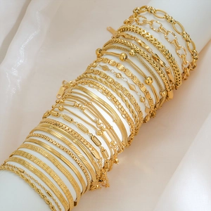 Collection of assorted gold-plated stainless steel bead and link anklets on a white stand
