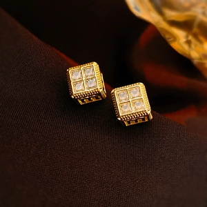 Close-up of gold-plated square stud earrings with four cubic zirconia stones and milgrain edges