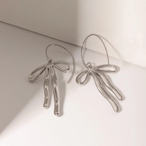 Detail of silver liquid metal bow earrings with a polished finish and hook design