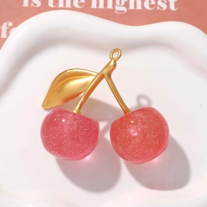 Macro shot of glittery red cherry pendant with gold leaves for DIY keychain and bag charm