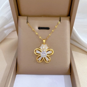 Gros plan détaillé d'un collier fleur en or avec zircon blanc dans un coffret cadeau beige
