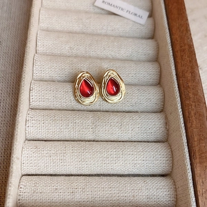 Detail of vintage red teardrop earrings in gold settings on a rustic jewelry tray