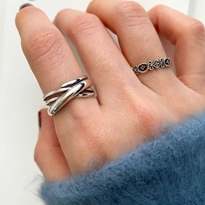 Macro shot of 925 sterling silver braided ring and vintage crossover band on hand