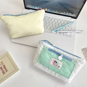 Close-up of minimalist canvas pencil cases with zippers on a tidy white desk setup