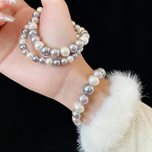 Elegant multi-layer pearl bracelet featuring white and grey pearls on a model wrist