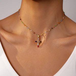 Close-up of beaded choker necklace with a colorful rhinestone cross pendant on model