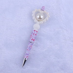 Macro detail of cartoon heart pen featuring a large faux pearl and LOVE pattern print