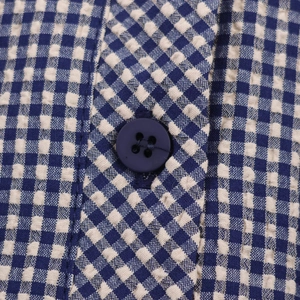 Gros plan sur un tissu seersucker à carreaux bleus et blancs avec un bouton bleu marine