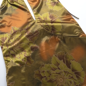 Detailed macro view of bronze satin fabric with yellow-green floral pattern and silky texture
