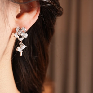 Détail de boucles d'oreilles fleurs en argent avec zircons portées par un modèle