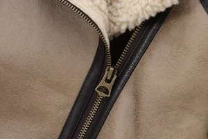 Detailed close-up of premium bronze metal zipper and soft cream wool lining on brown jacket