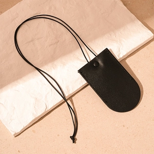 Close-up of black leather key pouch necklace with snap button on a natural stone slab