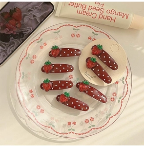 Detailed set of strawberry and polka dot hair clips displayed on a wooden plate
