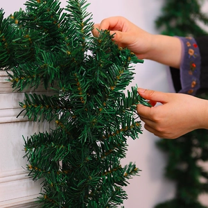 Close-up of dense green Christmas garland with PE pine needles on a white fireplace