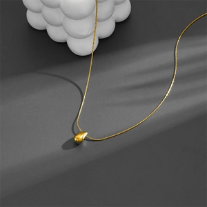 Polished gold-plated teardrop pendant necklace on a minimalist decorative background