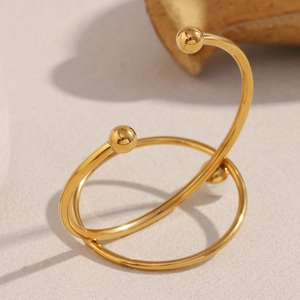 Detail of 18K gold plated knotted metal bangle featuring a minimalist crossover pearl design