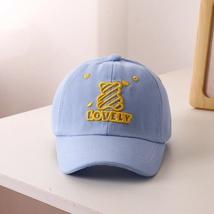Detail of baby baseball cap featuring yellow cartoon bear and LOVELY embroidery in blue