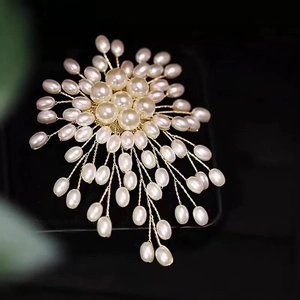 Elegant handmade pearl flower brooch with gold wire wrap on black jewelry box background