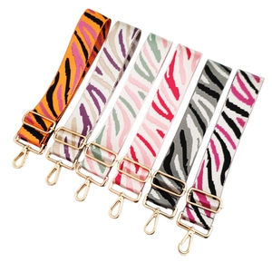 Detail of adjustable zebra pattern woven bag straps with high-quality gold metal hooks