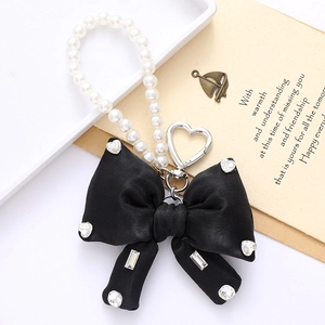 Detailed view of a black ribbon bow charm with sparkling rhinestones and white pearls