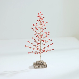 Red Christmas berry tree decoration with golden glitter base on light gray background
