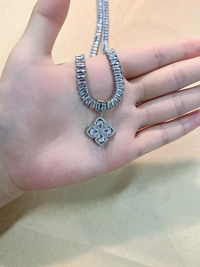 Detailed macro of a silver clover necklace with sparkling cubic zirconia on silk
